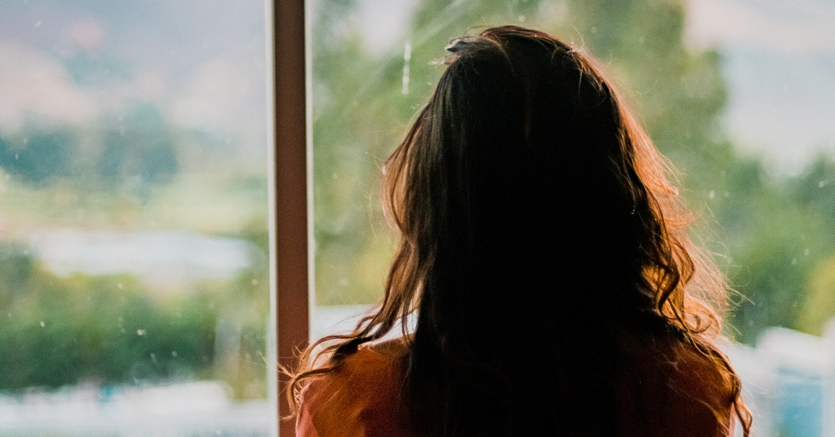 A woman looks out a window at her city from above. Addiction therapy isn't just about individual achievement; It can promote community resilience.