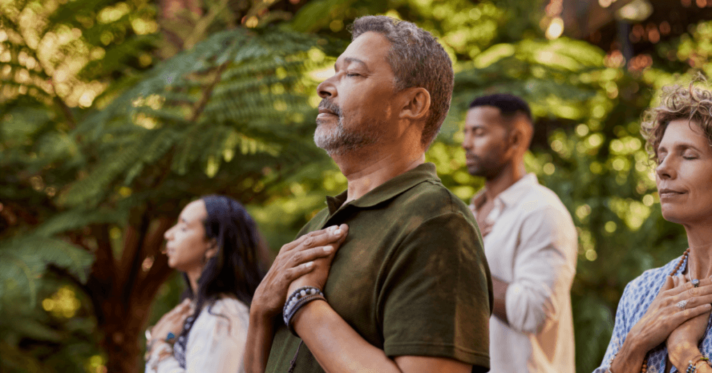 A diverse group practicing mindfulness outdoors at Crest View Recovery Center, supporting loving yourself in recovery in a serene, natural setting.