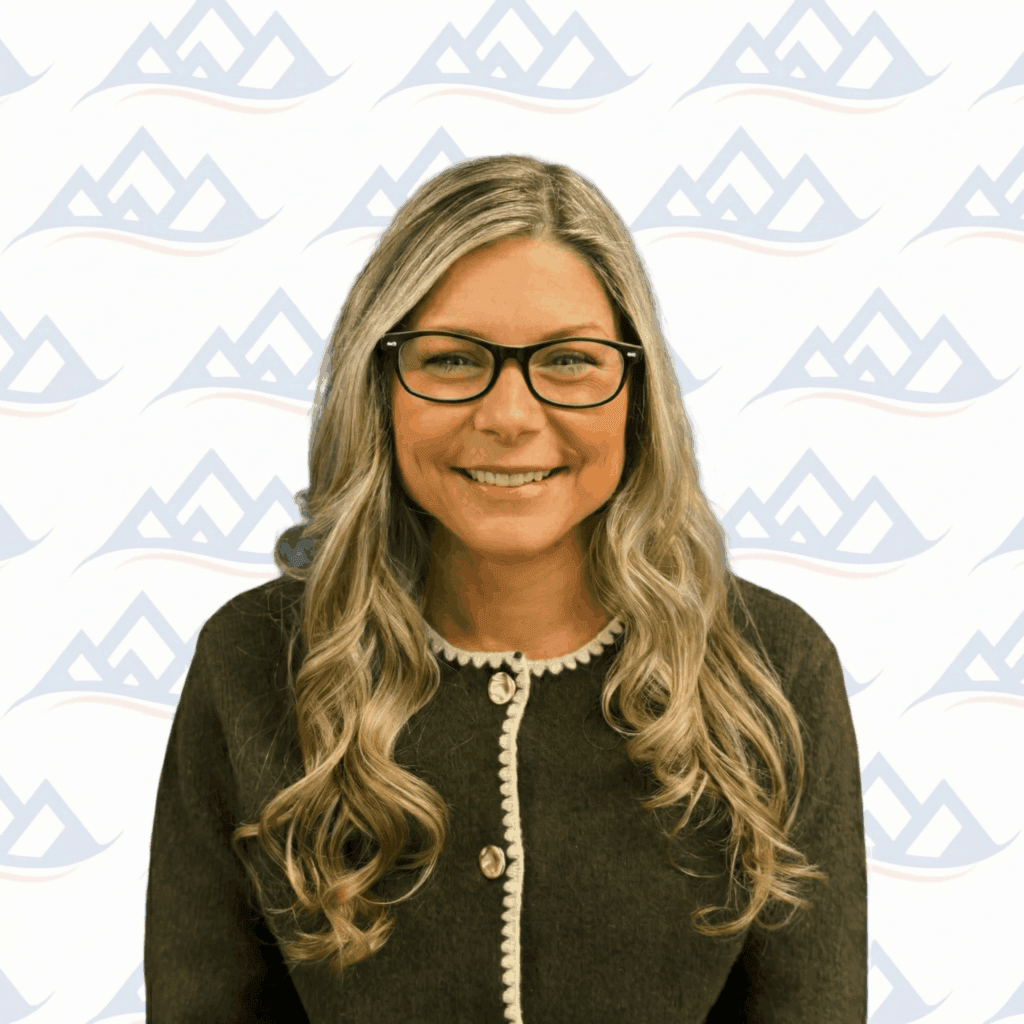 A certified addiction professional at Crest View Recovery Center smiles in front of our blue mountain logo, representing outpatient rehab.