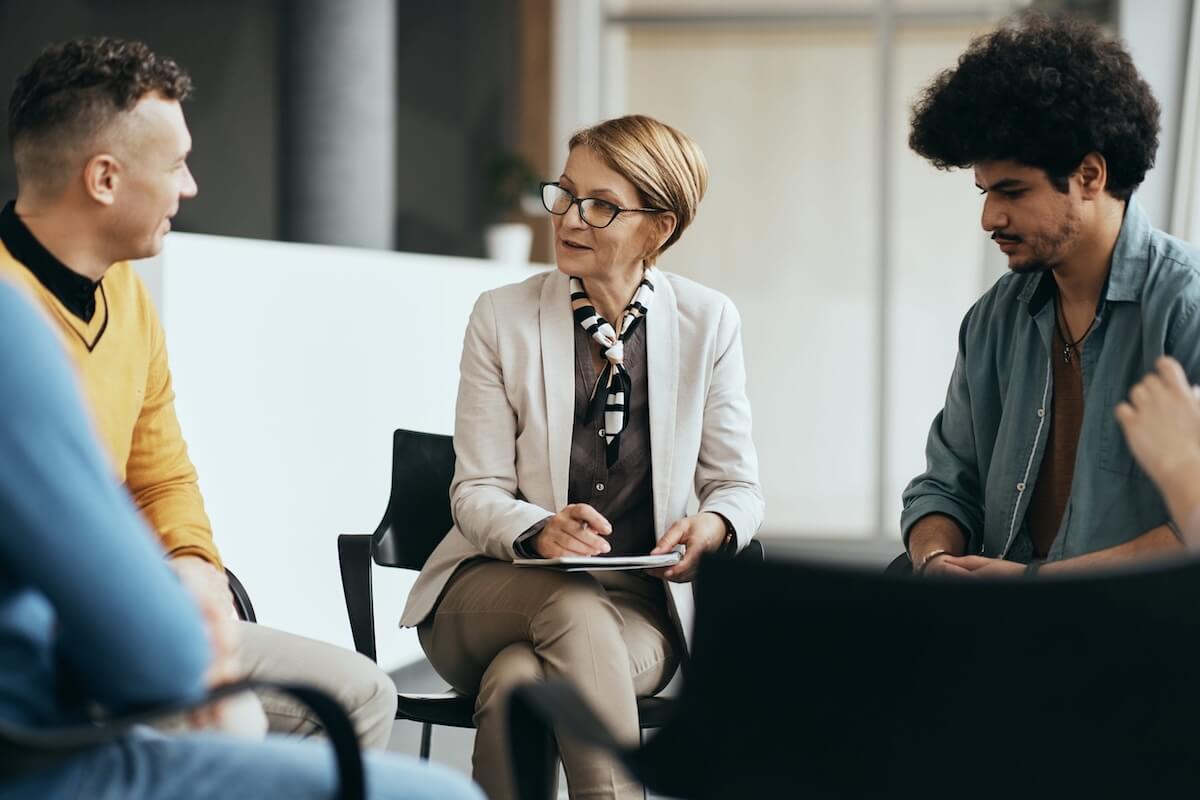 Clients participate in group therapy at a North Carolina outpatient addiction treatment center; woman takes notes during discussion.
