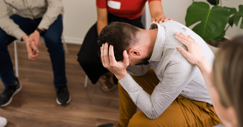 A distressed person in a drug and alcohol support group receives comfort from peers at Crest View Recovery Center about the benefits of counseling for addiction recovery.