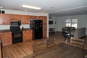 Open-plan kitchen and living area with wood floors, brown cabinets, dining table, and cozy seating—perfect for outpatient recovery clients.