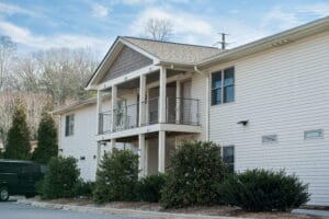 Two-story beige housing near Crest View Recovery Center, Asheville NC outpatient addiction treatment, green van out front, cloudy sky.