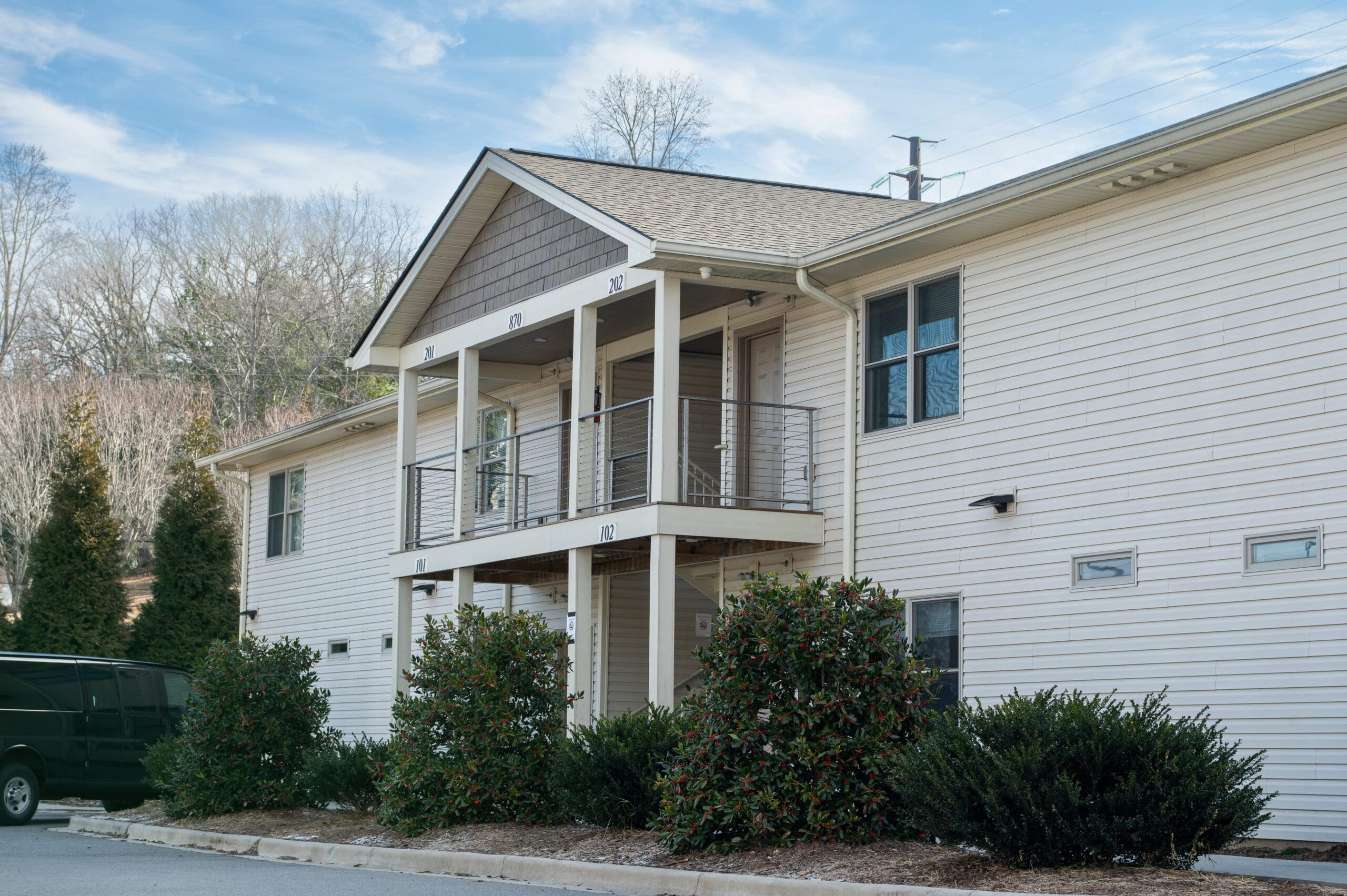 Two-story beige housing near Crest View Recovery Center, Asheville NC outpatient addiction treatment, green van out front, cloudy sky.